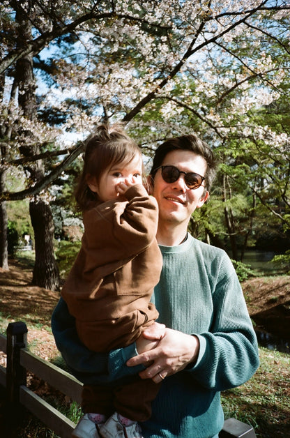 Man holding a child under cherry blossom trees